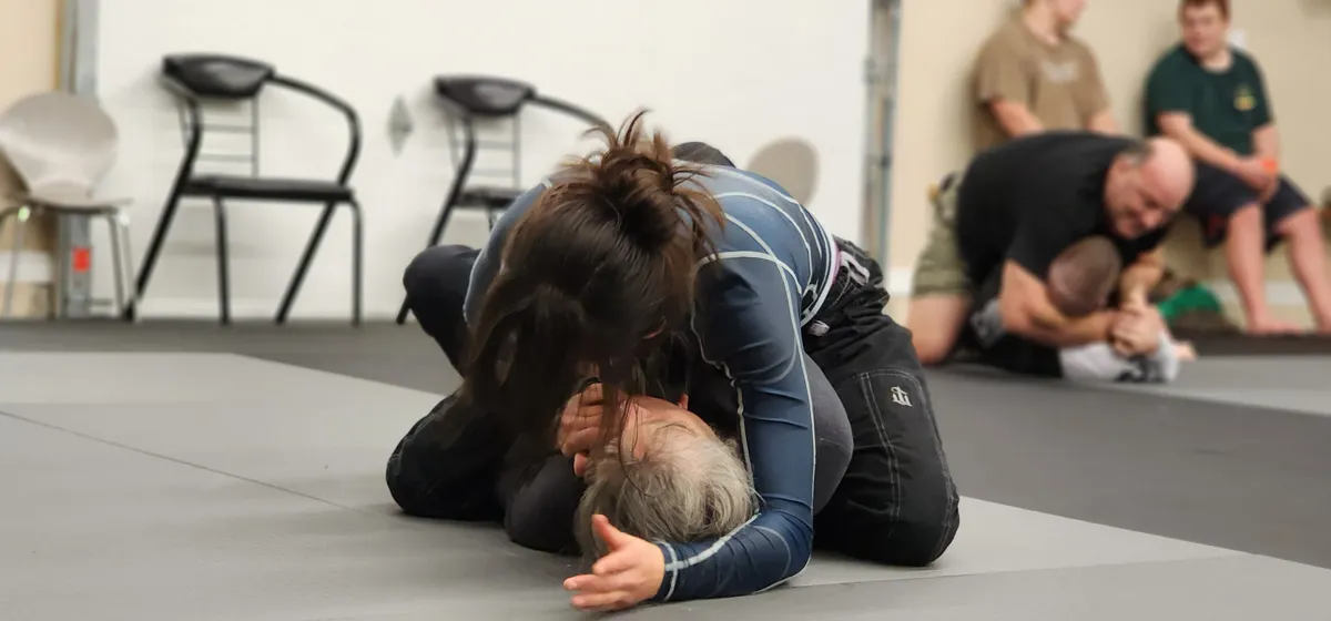 Two students rolling on the mat in a Women's Self Defense class